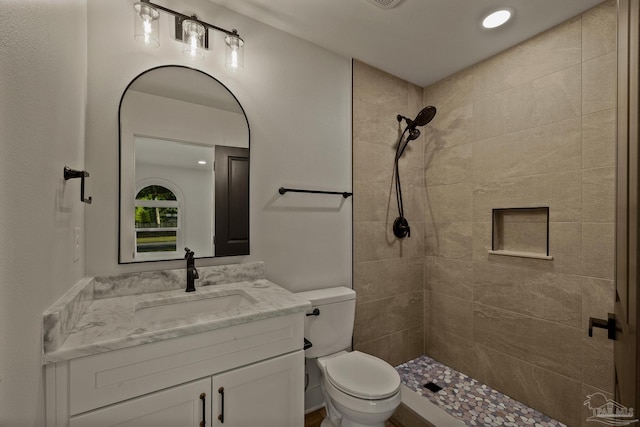 full bath featuring tiled shower, vanity, recessed lighting, and toilet