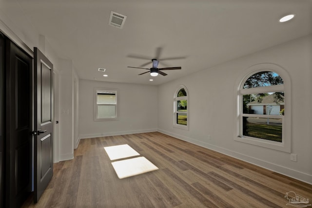 empty room featuring a wealth of natural light, light wood-style floors, and visible vents