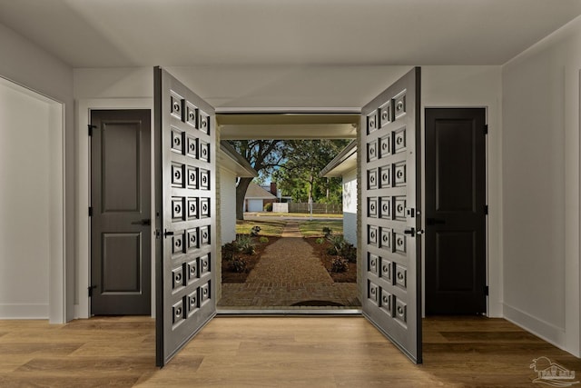 doorway with wood finished floors and baseboards