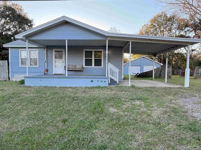 view of front of home featuring an outbuilding, covered porch, a front yard, fence, and an attached carport