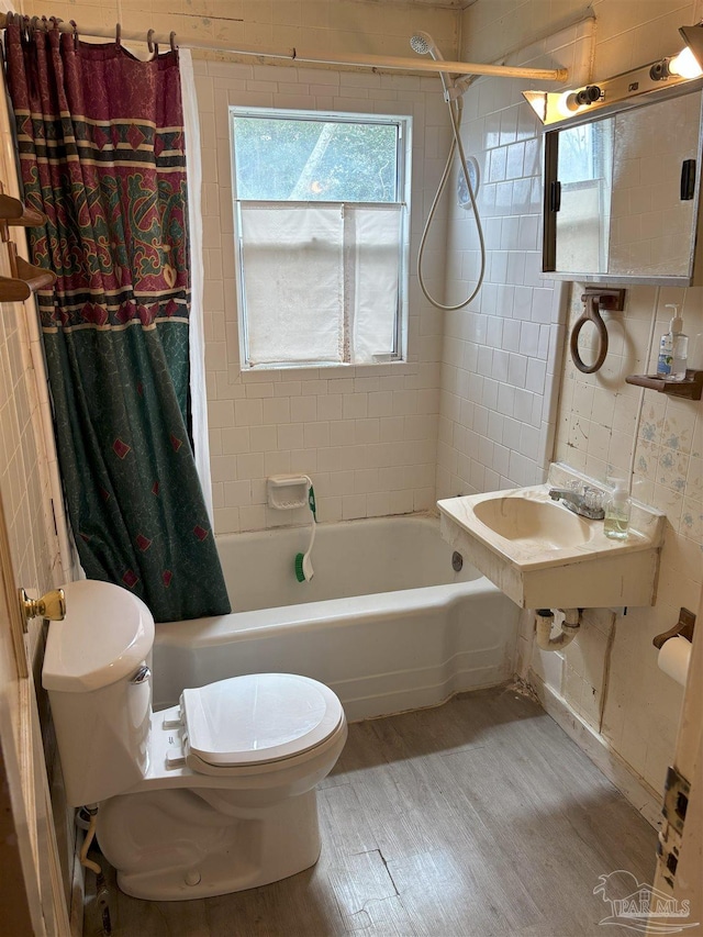 bathroom with a sink, wood finished floors, toilet, and shower / bathtub combination with curtain