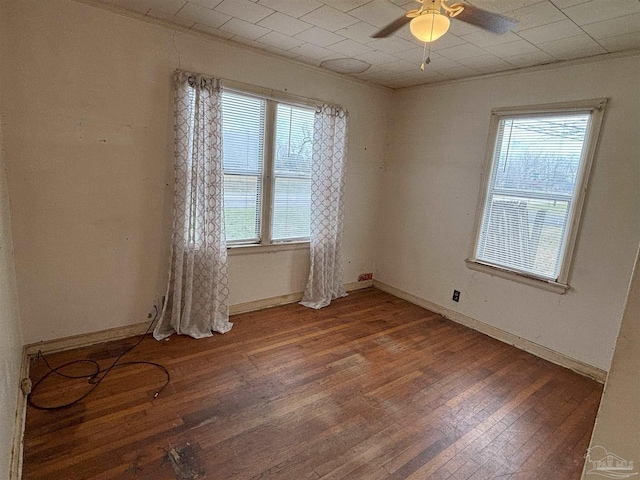 spare room featuring baseboards, wood finished floors, a wealth of natural light, and crown molding