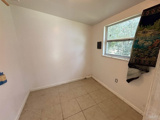 empty room with baseboards and light tile patterned flooring