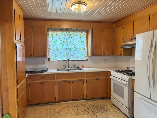 kitchen with light floors, light countertops, a sink, white appliances, and under cabinet range hood