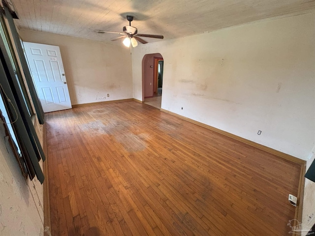 spare room with light wood finished floors, ceiling fan, arched walkways, and baseboards