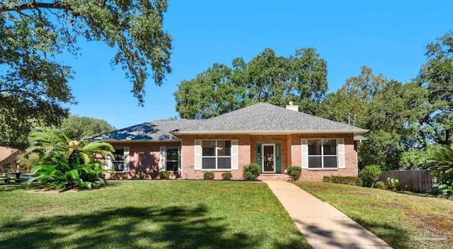 view of front of house featuring a shingled roof, brick siding, fence, a front lawn, and a chimney