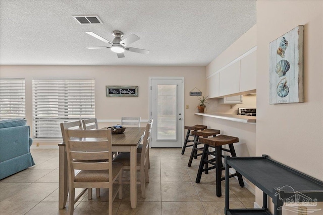 dining space with visible vents, ceiling fan, a textured ceiling, and light tile patterned floors