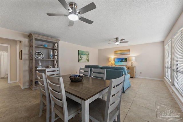 dining space featuring light tile patterned floors, a textured ceiling, and baseboards