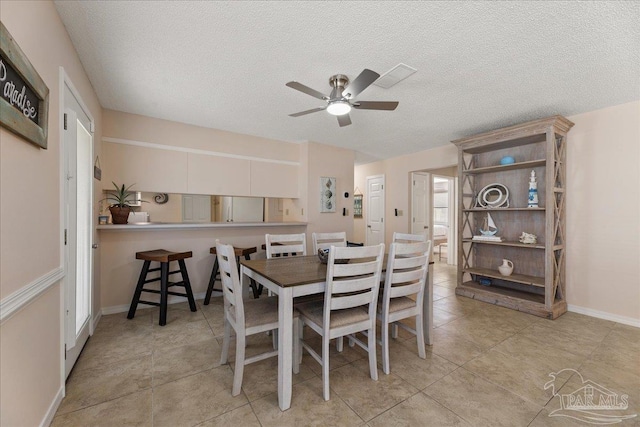 dining space with ceiling fan, baseboards, a textured ceiling, and light tile patterned flooring