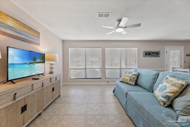 living room featuring baseboards, visible vents, ceiling fan, a textured ceiling, and light tile patterned flooring