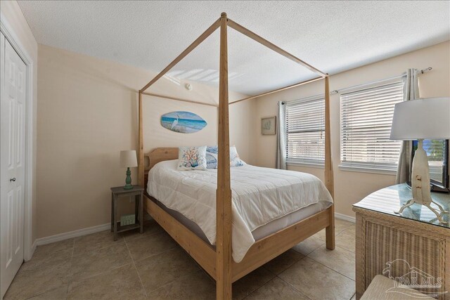 tiled bedroom featuring a textured ceiling and baseboards