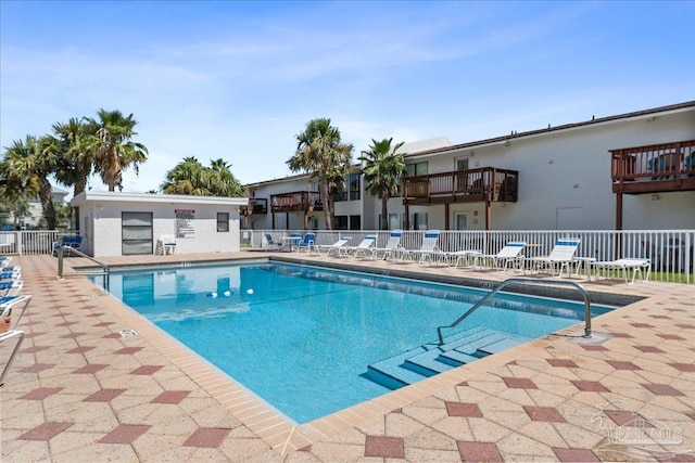 community pool with a patio area and fence