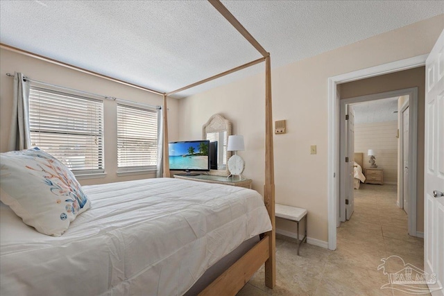 bedroom featuring a textured ceiling, light tile patterned floors, and baseboards