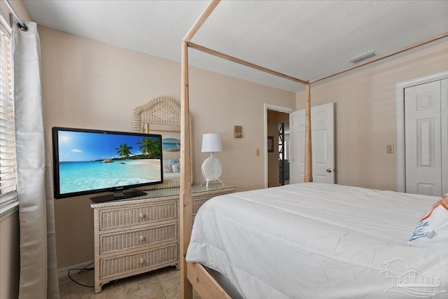 bedroom with visible vents, a textured ceiling, and tile patterned floors