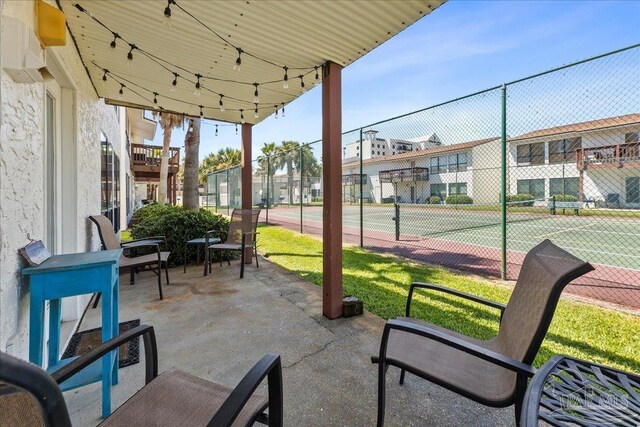 view of patio / terrace featuring a tennis court and fence