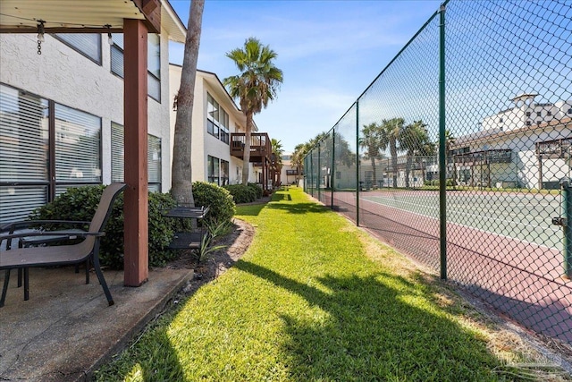 view of sport court with fence and a lawn