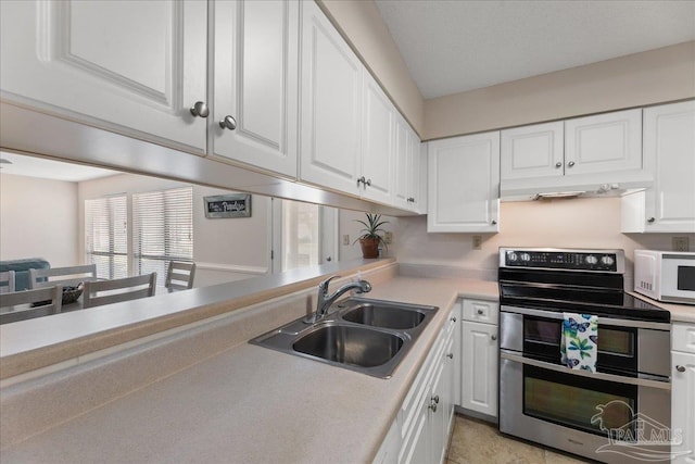 kitchen with white microwave, a sink, white cabinetry, light countertops, and double oven range