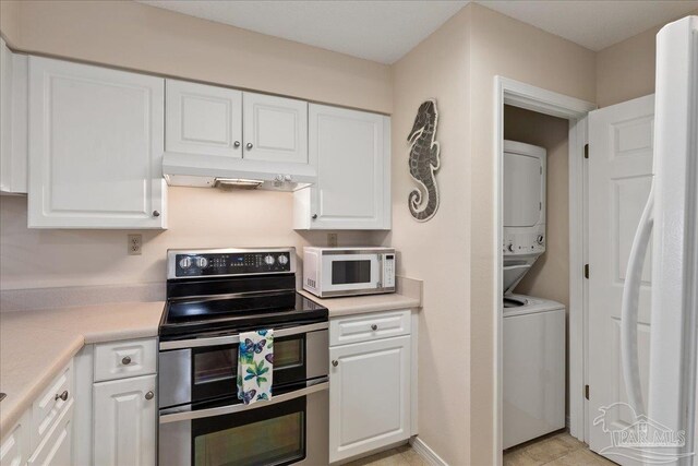 kitchen with white appliances, white cabinets, stacked washer and clothes dryer, light countertops, and exhaust hood