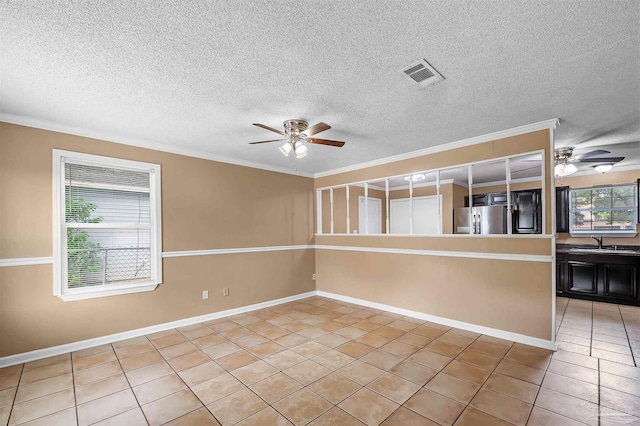 tiled empty room with ceiling fan, a textured ceiling, crown molding, and sink