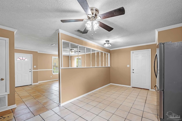 kitchen with a textured ceiling, light tile patterned floors, crown molding, ceiling fan, and stainless steel fridge