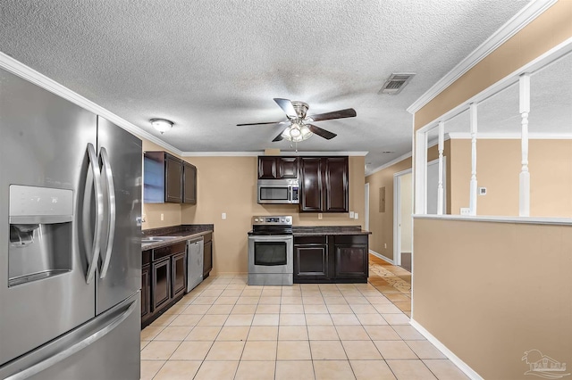 kitchen with stainless steel appliances, a textured ceiling, light tile patterned flooring, and crown molding