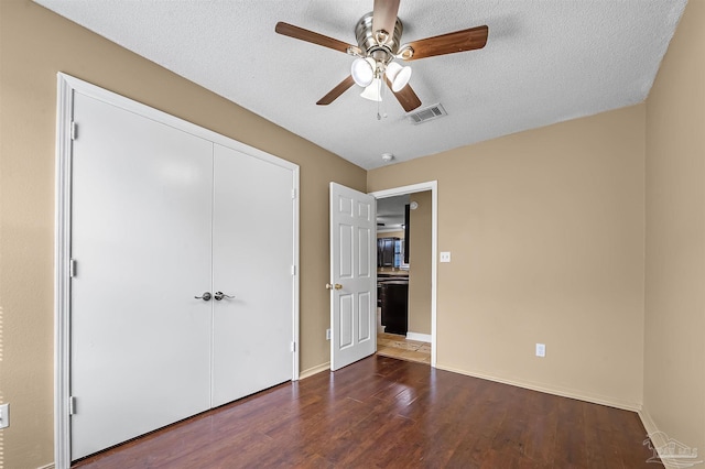 unfurnished bedroom with a closet, a textured ceiling, ceiling fan, and dark hardwood / wood-style flooring