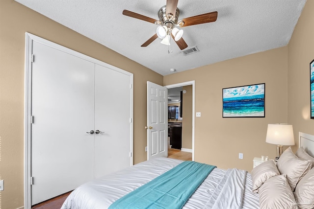 bedroom with ceiling fan, a textured ceiling, a closet, and wood-type flooring