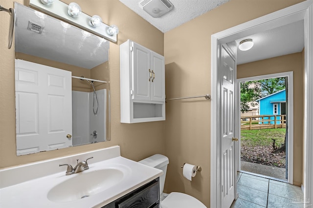 bathroom with tile patterned flooring, a textured ceiling, walk in shower, vanity, and toilet