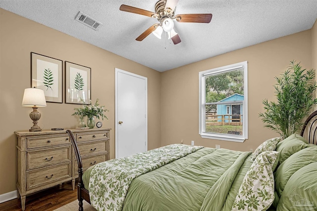 bedroom with a textured ceiling, ceiling fan, and hardwood / wood-style flooring