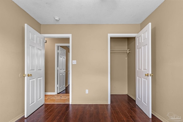 unfurnished bedroom featuring a textured ceiling, a closet, and dark hardwood / wood-style flooring