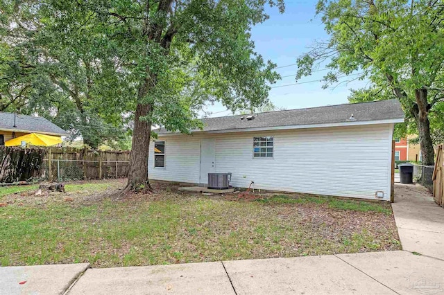 rear view of property with a yard and central AC unit