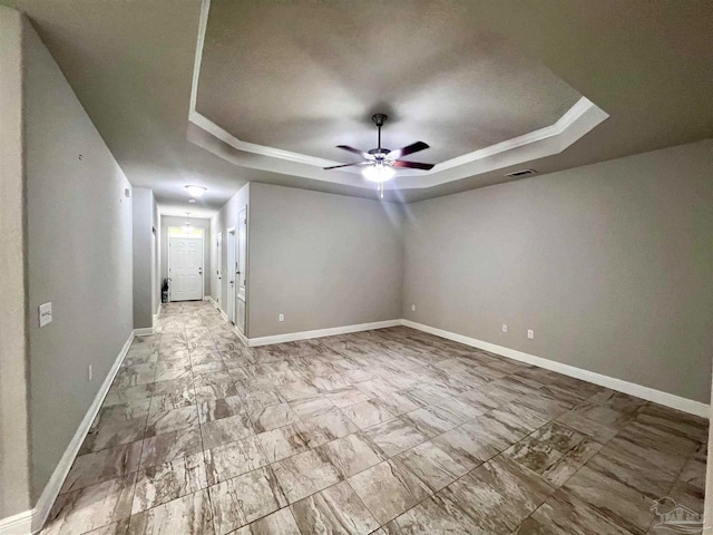 spare room with a raised ceiling, crown molding, and ceiling fan