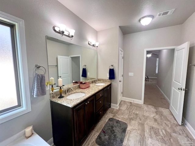 bathroom featuring ceiling fan, vanity, and a textured ceiling