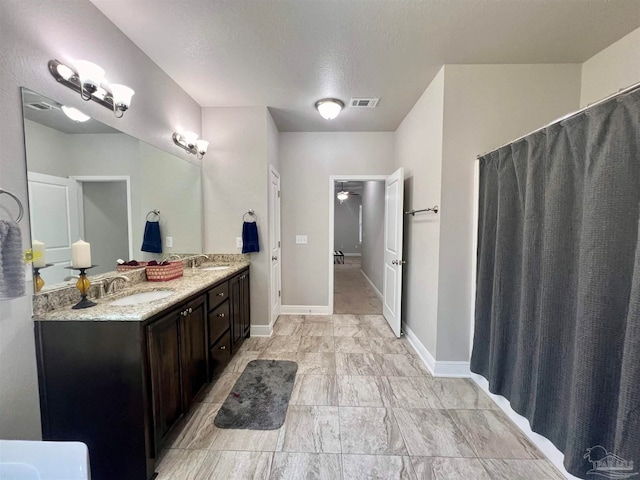 bathroom with a textured ceiling, vanity, and ceiling fan