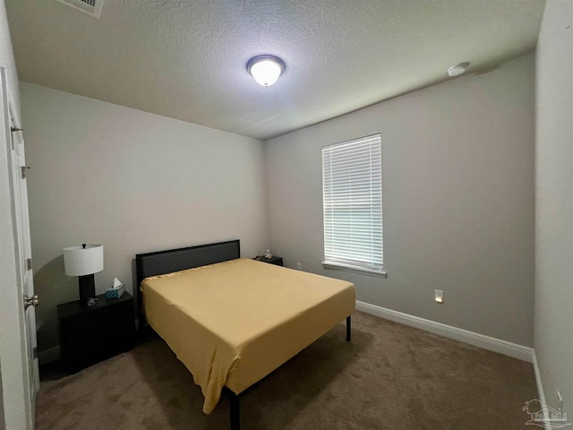 bedroom featuring a textured ceiling and dark colored carpet