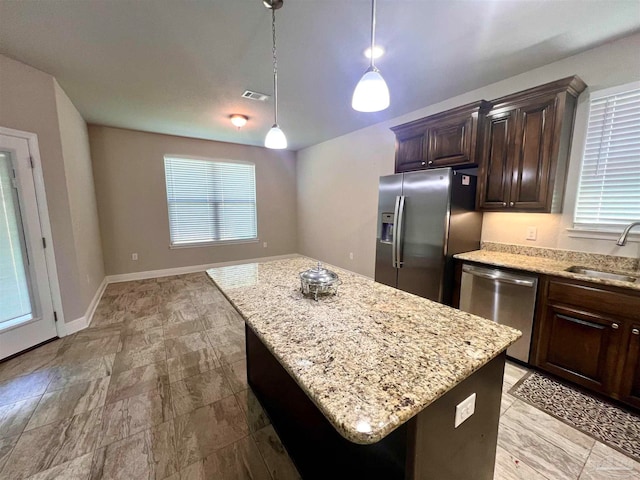 kitchen featuring hanging light fixtures, a kitchen island, stainless steel appliances, dark brown cabinets, and sink