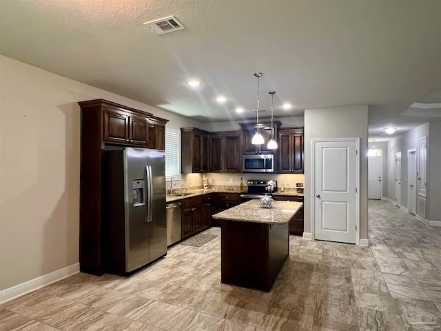 kitchen featuring dark brown cabinetry, pendant lighting, sink, a kitchen island, and appliances with stainless steel finishes