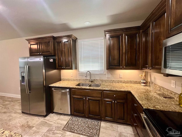 kitchen with dark brown cabinets, sink, stainless steel appliances, and light stone counters