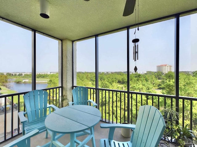 sunroom / solarium with outdoor dining area, a ceiling fan, and a water view