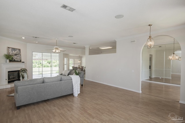 3221 Cobblestone Dr, Pace, FL 32571 - living area featuring a glass covered fireplace, ornamental molding, arched walkways, wood finished floors, and ceiling fan
