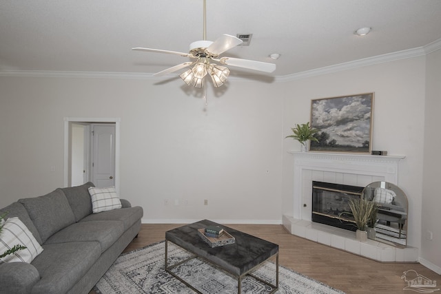 3221 Cobblestone Dr, Pace, FL 32571 - living room featuring ceiling fan, ornamental molding, wood finished floors, a tiled fireplace, and baseboards
