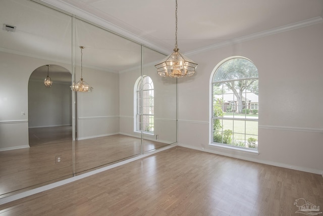 3221 Cobblestone Dr, Pace, FL 32571 - empty room with a chandelier, wood finished floors, baseboards, crown molding, and arched walkways