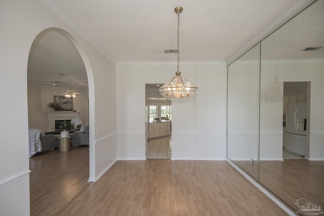 3221 Cobblestone Dr, Pace, FL 32571 - unfurnished dining area featuring wood finished floors, a fireplace, arched walkways, a chandelier, and ornamental molding