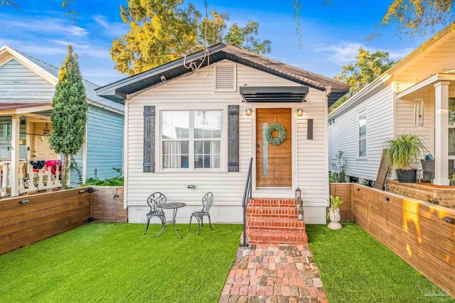 shotgun-style home with entry steps, fence, and a front yard