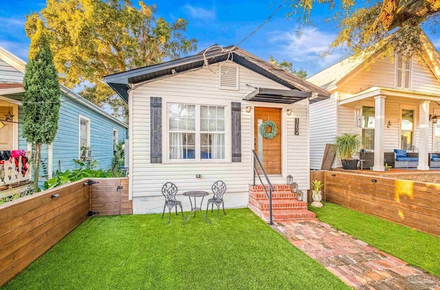 shotgun-style home with entry steps, fence, and a front lawn