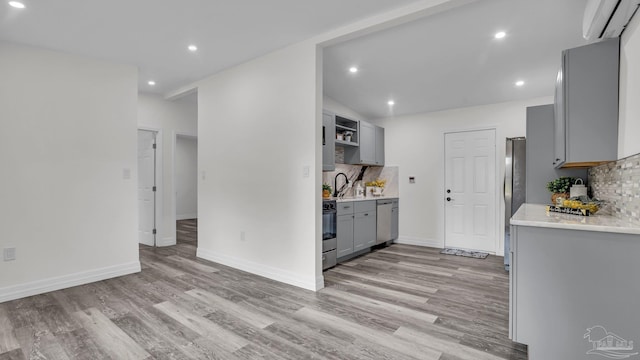 kitchen featuring appliances with stainless steel finishes, light hardwood / wood-style flooring, decorative backsplash, and gray cabinetry