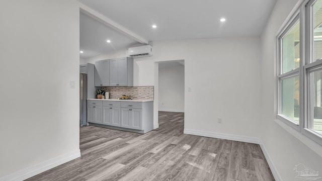 kitchen with light hardwood / wood-style flooring, a wall mounted AC, and a wealth of natural light