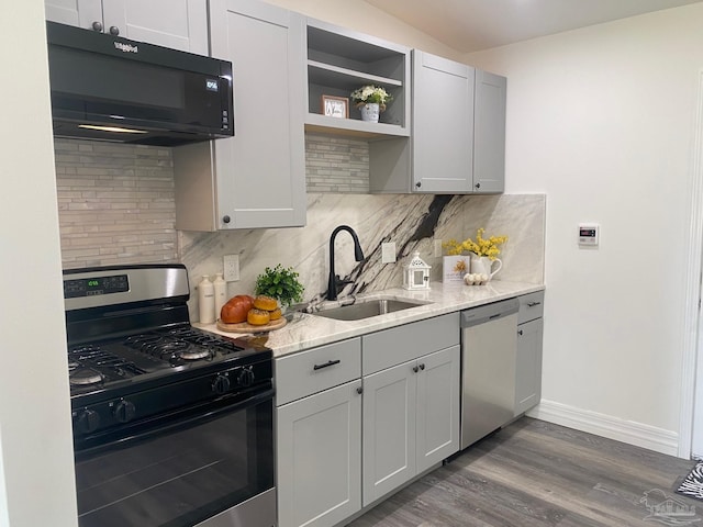 kitchen featuring backsplash, light stone countertops, hardwood / wood-style flooring, sink, and stainless steel appliances