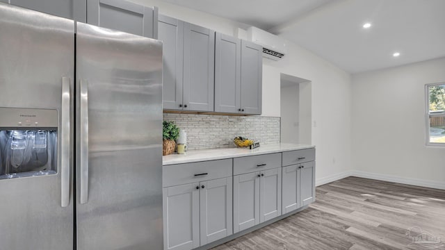 kitchen featuring an AC wall unit, stainless steel refrigerator with ice dispenser, light wood-type flooring, and gray cabinets