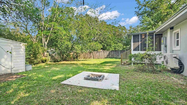 view of yard featuring ac unit, a storage shed, an outdoor fire pit, and a sunroom